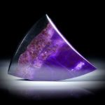 Sugilith Freiform 70.77ct.  Zahnform poliert, mit natürlichem Übergang in Manganerz, ca.42x38x7mm